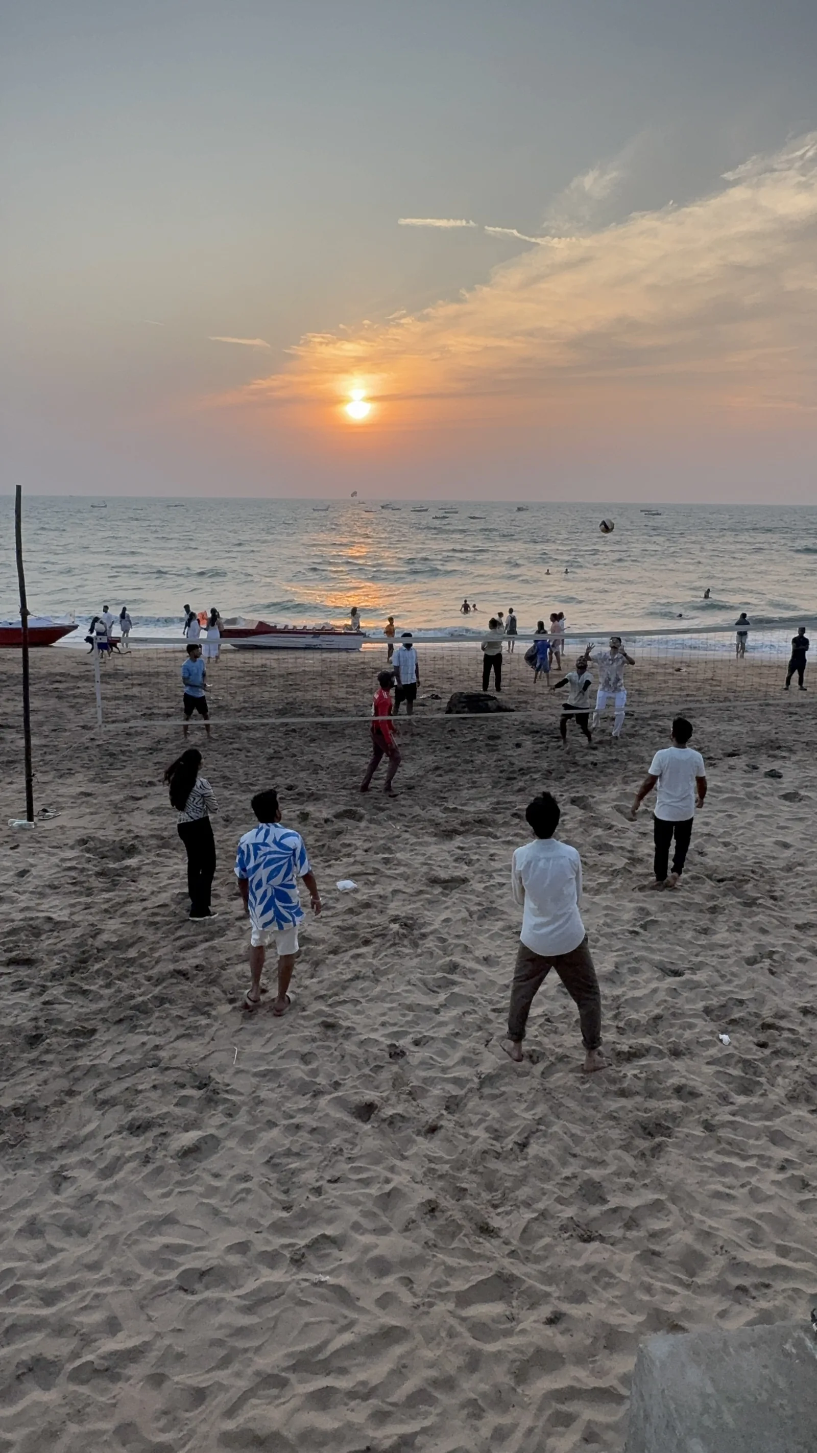 The team playing beach volleyball beside the sea at sunset